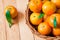 Fresh organic tangerines in a wicker basket on a wooden table