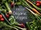 \'Fresh Organic Veggies\' poster design. Young spring vegetables on black.