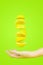 Fresh organic yellow lemon fruit slice levitation falling suspended in the air above hand on green background . Summer refreshing