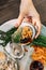 Fresh Oysters in shell in hand that topping with fried shallot, chili paste, Acacia Pennata and Thai style seafood sauce