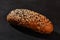 Fresh, palatable baked bread sprinkled with black and white sesame seeds against black background with copy space. Rural