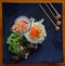 Fresh Palm Salad with Prawn Skewers in a glass on a black square plate with top down view