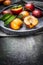 Fresh peaches with green leaves in stone plate on dark background