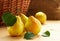 Fresh pears with leaves in front of wattled basket with harvest on wooden rustic background, copy space