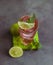 A fresh pink cocktail or mocktail drink with lime, pink grapefruit juice and mint, green background. Paloma