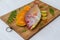 fresh Pink Perch (thread finned Bream) Decorated with lemon slice Orange slice and curry leaves on a wooden pad.