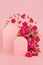 Fresh pink roses as arch, two empty rounded doors as podiums with green leaves, buds soar as frame on abstract pink scene mockup.