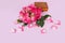 Fresh pink roses in a wooden box on a pink background. Flying rose petals. View from above