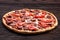 Fresh pizza with tomatoes, cheese, onions and sausage on wooden table closeup