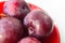 fresh plum fruit in the red saucer on white background