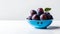 Fresh plums in a blue bowl on a light background