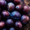 Fresh plums on a dark wood background. Top view image. Ripe Plu