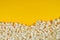 Fresh popcorn on a yellow background with copy space. Top view. Cinema and entertainment concept