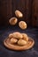 Fresh potatoes soaring above the wooden plate on wooden textured background. Organic food, carbs, tubers.