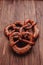 Fresh pretzel sprinkled with sesame seeds on a wooden background