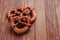 Fresh pretzel sprinkled with sesame seeds on a wooden background