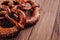 Fresh pretzel sprinkled with sesame seeds on a wooden background