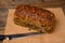 A fresh pumpkin seed bread from the baker on a jute fabric and a bread knife