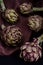 Fresh purple artichokes on black background