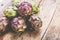 Fresh purple artichokes on dark rustic wooden background .