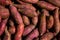 Fresh purple yams pile. Sweet potato for sale in local market. cofred yam background, pile of red or purple yam on background.