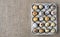 Fresh quail eggs in open cardboard packaging on flaxen background. Top view, copy space