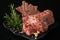 Fresh rack of lamb on a black plate on a dark background with spices: rosemary, pepper, salt