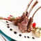 Fresh rack of lamb, carra d\\\'agneau, on a white plate with herbs, rosemary, basil and sauces. AI generated