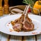 Fresh rack of lamb, carra d\\\'agneau, on a white plate with herbs, rosemary, basil and sauces. AI generated