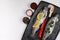 Fresh rainbow trouts on black board on table with salt, pepper, lemon and chili pepper ingredients, flatlay, copy space