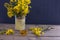 Fresh rapeseed flowers stand in a vase, near rapeseed oil on a wooden table