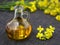 fresh rapeseed oil in glass bottle decanter with rape flowers on dark background