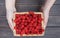 Fresh raspberries basket in woman\'s hands on wood background