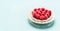 Fresh raspberries in white bowl standing on light turquoise background, copy space