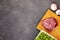 Fresh raw beef on a chopping Board with vegetables and microgreens on a black marble background, top view