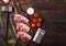 Fresh raw butchers lamb beef cutlets on chopping board with vintage meat hatchet and hammer on wooden background.Salt, pepper and