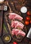 Fresh raw butchers lamb beef cutlets on chopping board with vintage meat hatchet and hammer on wooden background.Salt, pepper and