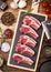 Fresh raw butchers lamb beef cutlets on chopping board with vintage meat hatchet and hammer on wooden background.Salt, pepper and