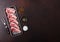 Fresh raw butchers lamb beef cutlets in plastic tray with vintage meat fork on brown background.Salt, pepper and oil in steel bowl