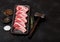 Fresh raw butchers lamb beef cutlets in plastic tray with vintage meat hammer on black background.Salt, pepper and oil in steel