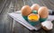 Fresh raw chicken eggs in an cartons egg box. Broken egg, yolk. Organic food for good health high protein on rustic wooden
