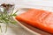 Fresh raw chilled salmon fillet a plate, pepper grains and rosemary on a wood kithen table. Healthy eating, seafood recipe