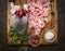 Fresh raw chopped turkey,meat cleaver, meat fork, salt ,pepper, hot peppers and fresh herbs on a wooden cutting board on rustic w