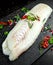 Fresh Raw Cod loin fillet with rosemary, chillies, cracked pepper and lemon on stone board