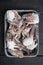 Fresh raw flower crab or blue crab frozen parts, in plastic tray, on black wooden table background, top view flat lay