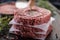 Fresh raw ground beef patties with rosemary salt and pepper made in a meat form on a cutting board