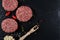 Fresh raw meat burger cutlet on the black slate board with herbs and spices for background.