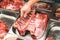 Fresh raw meat, pork ribs in supermarket. Butcher shop. Butcher`s hands holding pork spare ribs for sale. Butcher`s display
