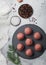 Fresh raw minced beef meatballs on round stone board with pepper, salt and garlic on light background with dill and towel