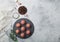 Fresh raw minced beef meatballs on round stone board with pepper, salt and garlic on light background with dill and towel